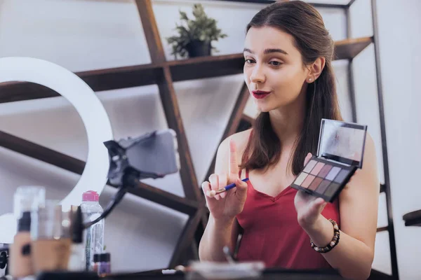 Dark-haired woman with red lips filming beauty blog — стоковое фото